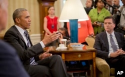 President Barack Obama, left, speaks to members of the media in the Oval Office of the White House in Washington, June 13, 2016.