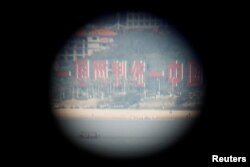 China's banner reading "One Country, Two Systems, One Unified China" is seen through a tourist's binoculars from a former military fort, ahead of the 60th anniversary of Second Taiwan Straits Crisis against China, in Lieyu island, Kinmen county, Taiwan, Aug. 20, 2018.