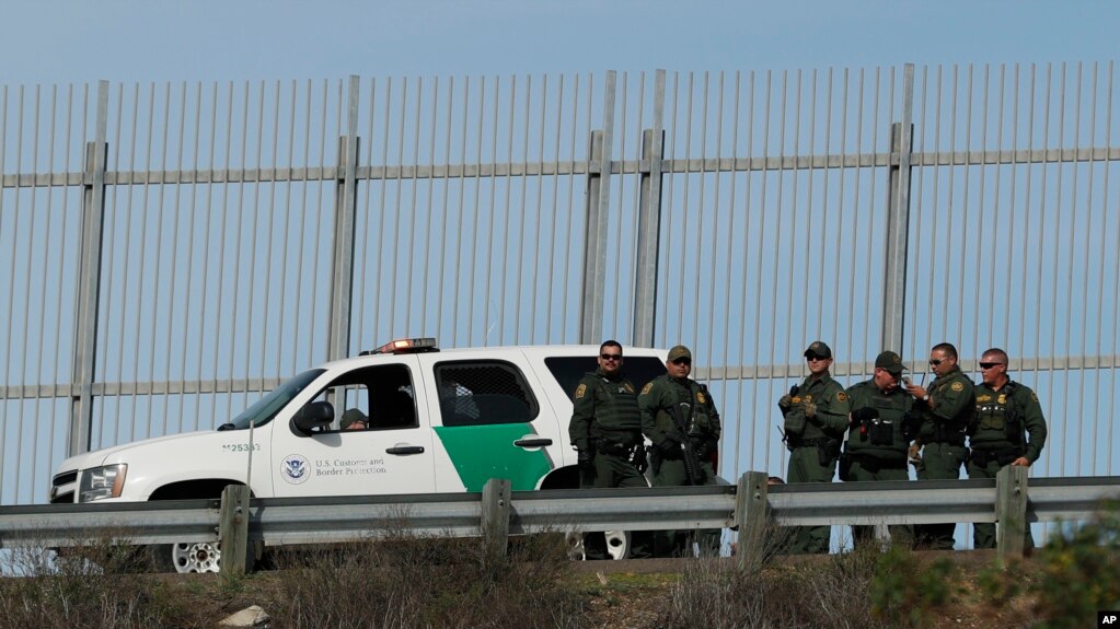 Agentes de la Patrulla Fronteriza de Estados Unidos frente a una valla secundaria en San Diego, California, observan el otro lado de la frontera mientras responden a un grupo de migrantes centroamericanos que cruzaron la frontera ilegalmente en Tijuana, México. 9 Dic.2018.