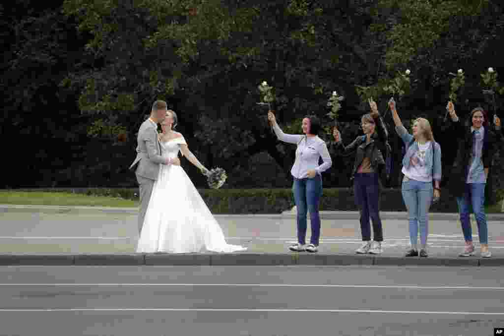 A newly wed couple kisses as opposition supporters hold flowers during a protest in Minsk, Belarus.