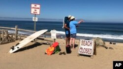 Two people look out at the shore after a shark attack at Newcomb Hollow Beach in Wellfleet, Mass, Sept. 15, 2018. A man boogie-boarding off the Cape Cod beach was attacked by a shark on Saturday and died later at a hospital, becoming the state’s first shark attack fatality in more than 80 years.