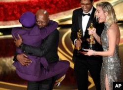 Samuel L. Jackson, center left, embraces Spike Lee, winner of the award for best adapted screenplay for "BlacKkKlansman" as Brie Larson, right, looks on, at the Oscars on Feb. 24, 2019, at the Dolby Theatre in Los Angeles.