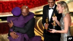 Samuel L. Jackson, center left, embraces Spike Lee, winner of the award for best adapted screenplay for "BlacKkKlansman" as Brie Larson, right, looks on, at the Oscars on Feb. 24, 2019, at the Dolby Theatre in Los Angeles. 