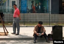 FILE - People waiting to apply for visas sit outside the U.S. embassy in Beijing, China, May 3, 2011.