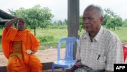 FILE - Meas Muth, right, sits next to a Buddhist monk at Anlong Veng district in Oddar Mean Chey province, Cambodia, July 23, 2006. Meas Muth was implicated in the 1975 Mayaguez incident in which at least 38 U.S. servicemen died.