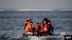 Des migrants, y compris des femmes et des enfants, dans un canot pneumatique, réagissent à l'approche de la côte sud de la Grande-Bretagne alors qu'ils traversent illégalement la Manche depuis la France le 11 septembre 2020.