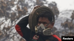 An Indonesian firefighter carries a fire hose as he walks after fighting burning palm oil trees at a palm oil plantation at Jebus village in Muaro Jambi, on the Indonesian island of Sumatra, September 16, 2015.