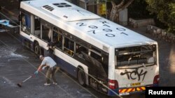 Israeli police explosive experts survey a damaged bus at the scene of an explosion in a Tel Aviv suburb Dec. 22, 2013.