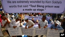 Cambodian protesters hold a banner, top, during a rally demanding Kem Sokha, vice president of Cambodia National Rescue Party (CNRP), to apologize in public, at Democracy Square, in Phnom Penh, Cambodia, Sunday, June 9, 2013. Cambodia's main opposition party denounced the large demonstration in the capital Sunday, which they said was staged by supporters of Prime Minister Hun Sen to intimidate rivals ahead of July elections. Banners, from left bottom, read " Kem Sokha is more cowardly than Duch," “ In our life we have never forgotten the torturers made by the teams of Po Pot,” “Kem Sokha has to take responsibility before the rule of law,” and “Kem Sokha is fighting against the Khmer Rouge Trial.” (AP Photo/Heng Sinith)