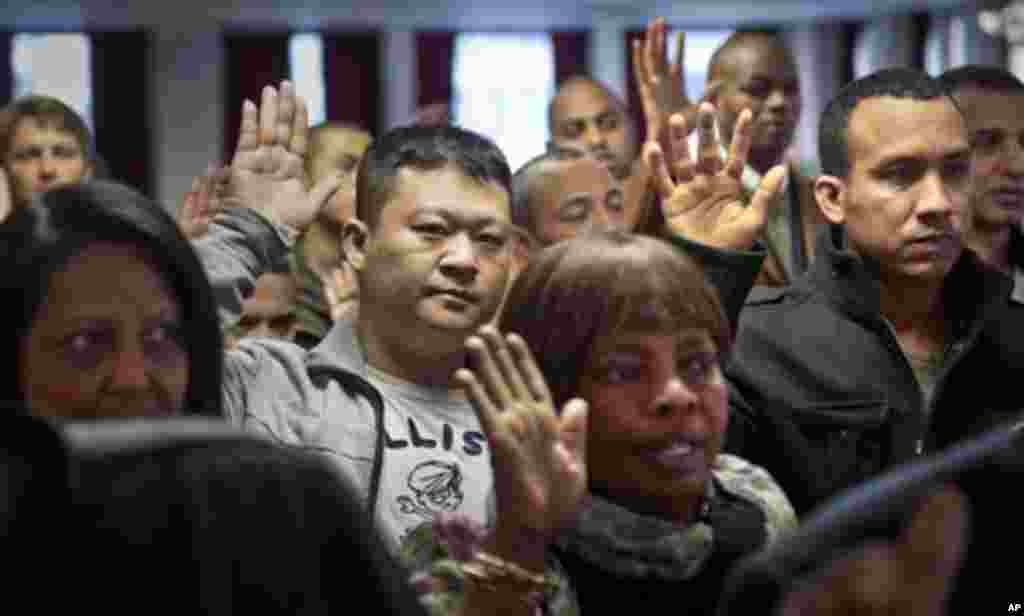 Para imigran mengangkat tangannya untuk menyatakan sumpah setia sebagai warga-warga negara baru dalam upacara naturalisasi di New York, 18 Desember 2013.&nbsp;(AP/Bebeto Matthews)