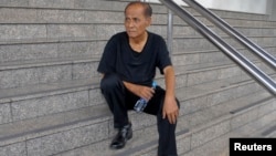 Chalad Vorachat, a retired navy lieutenant and serial hunger striker, sits on the steps of the criminal court in Bangkok, June 10, 2014. 