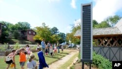 In this Wednesday, Oct. 9, 2019 photo, schoolchildren gather near a fake chimney meant as a nesting structure for chimney swifts in Birmingham, Ala. 