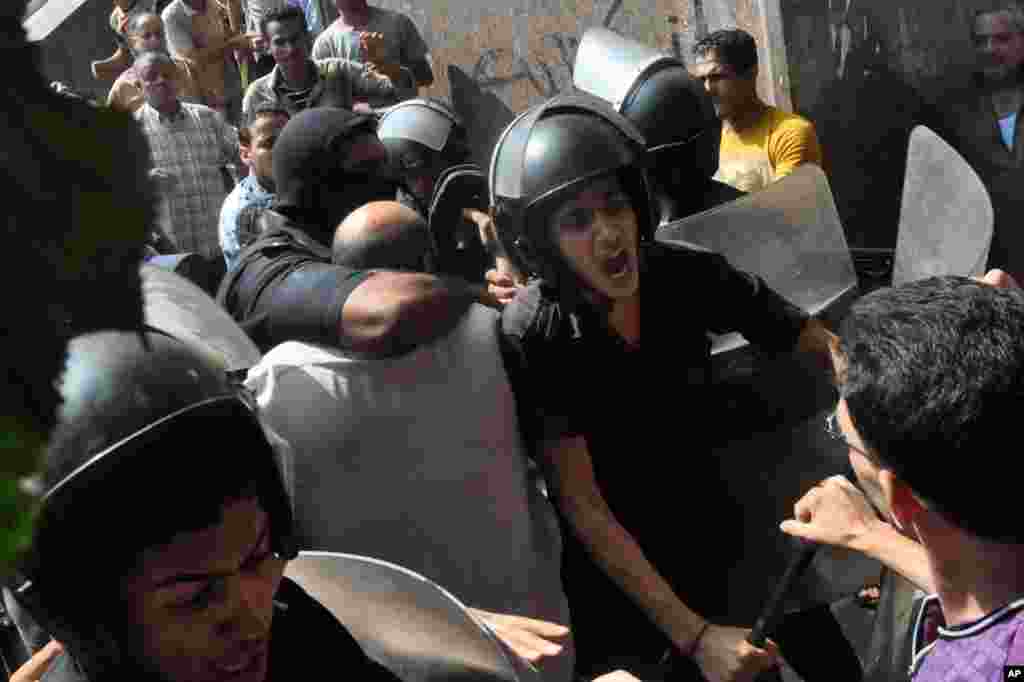 Pasukan keamanan Mesir menghalau demonstran keluar dari Masjid al-Fatah dan melewati kerumunan demonstran yang marah menyusul bentrokan yang menewaskan sejumlah orang dekat Lapangan Ramses di pusat kota Kairo (17/8). (AP/Hussein Tallal)