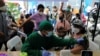 Seorang nakes tengah memeriksa kesehatan seorang perempuan sebelum disuntik vaksin booster COVID-19 di Jakarta, 12 Januari 2022. (REUTERS/Willy Kurniawan)