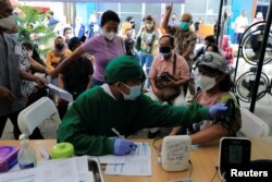 Petugas medis melakukan pemeriksaan kesehatan terhadap seorang perempuan yang akan menerima dosis vaksin booster di Jakarta, 12 Januari 2022.( Foto: REUTERS/Willy Kurniawan)