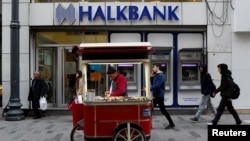 A street vendor sells roasted chestnuts in front of a branch of Halkbank in central Istanbul, Turkey, Jan. 10, 2018. 