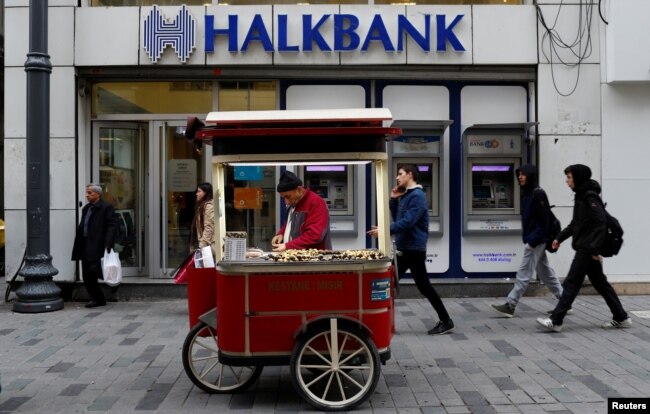 FILE - A street vendor sells roasted chestnuts in front of a branch of Halkbank in central Istanbul, Turkey, Jan. 10, 2018.