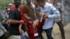 FILE - An election committee official, who has lost consciousness, is helped out of a polling station after an angry mob surrounded her in a protest against alleged election irregularities in Phnom Penh, July 28, 2013. 