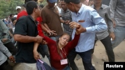 FILE - An election committee official, who has lost consciousness, is helped out of a polling station after an angry mob surrounded her in a protest against alleged election irregularities in Phnom Penh, July 28, 2013. 