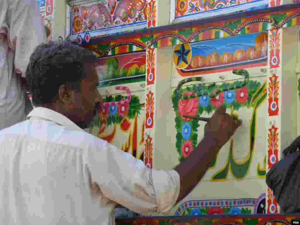 Men paint a bus, Islamabad, Pakistan, July 10, 2012. (S. Gul/VOA)