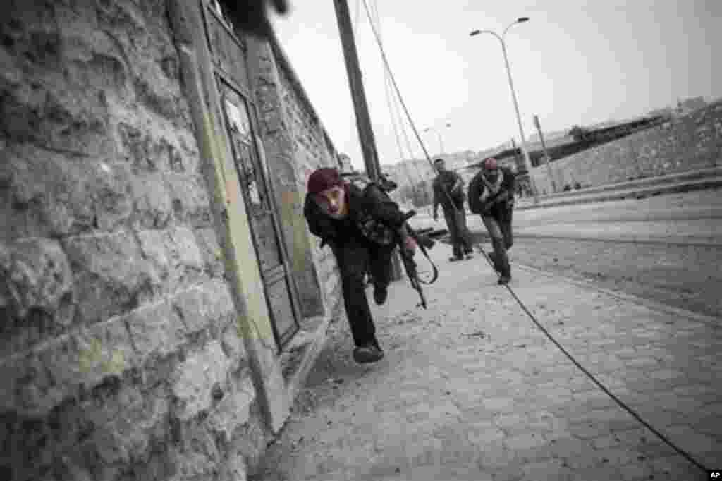 ໃນວັນທີ 21 ຕຸລາ 2012. ພວກນັກລົບກອງທັບປົດປ່ອຍຊີເຣຍ ແລ່ນໄປຊອກບ່ອນຫລົບໄພ ໃນຂະນະທີ່ແລ່ນຜ່ານ ລູກປືນຂອງພວກຈອບຍິງ ຢູ່ໃນຄຸ້ມ Bustan al-Qasr ຂອງນະຄອນ Aleppo ຂອງຊີເຣຍ. (AP Photo/Narciso Contreras) 