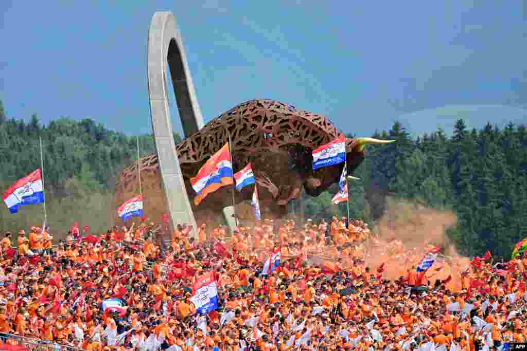 Supporters of Red Bull&#39;s Dutch driver Max Verstappen cheer from the stands near the large-scale jumping bull sculpture during the Formula One Austrian Grand Prix at the Red Bull Ring race track in Spielberg, Austria.
