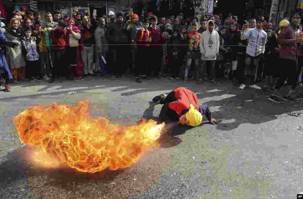 An Indian Sikh warrior blows fire as he demonstrations traditional martial art skills during a religious march.