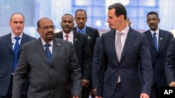 FILE - In this photo released by the Syrian official news agency SANA, Syrian President Bashar al-Assad, right, meets with Sudan's President Omar al-Bashir in Damascus, Syria, Dec. 16, 2018. 