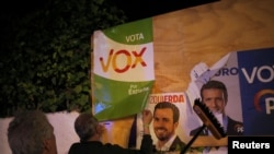 Members of Spain's far-right party VOX put up a campaign poster, while main candidates for Spanish general elections debate during a live televised debate ahead of general elections in Madrid, outside a polling station in Ronda, Spain April 22, 2019.