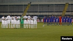 Players of the U.S. (in white) and of Ukraine (in blue) observe a minute of silence as a tribute to those who lost their lives in Kyiv during recent protests, before their international friendly soccer match in Larnaca, Cyprus, March 5, 2014.