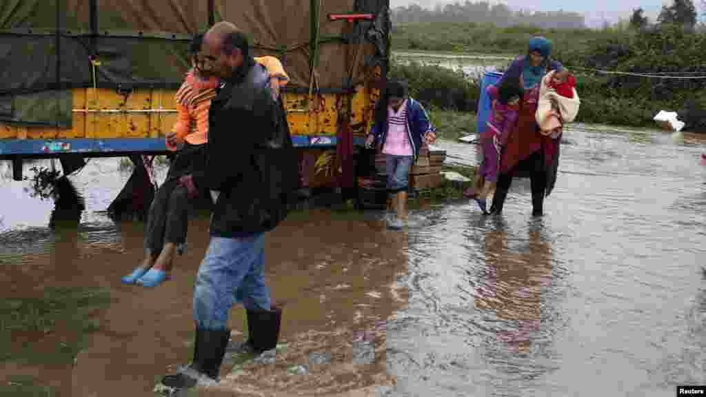 Syrian refugees make their way through flood after their tent was damaged at a makeshift settlement, during a wind storm in Akkar, northern Lebanon, Jan. 7, 2015. 