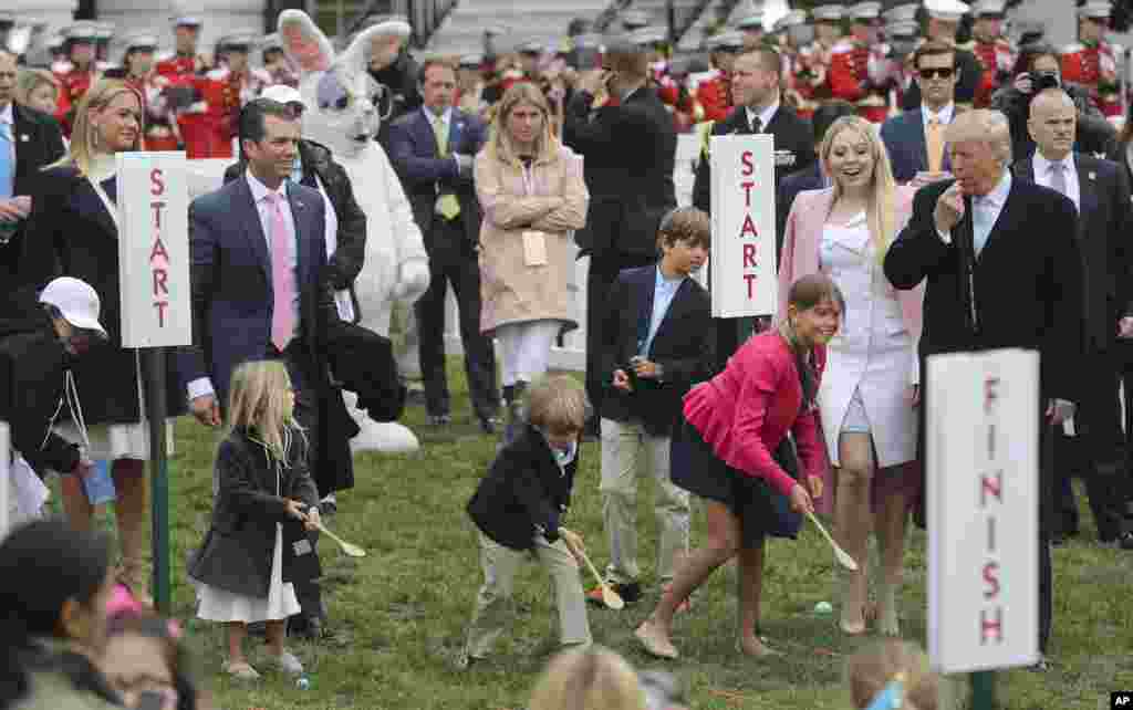 Presiden Donald Trump, kanan, meniup peluit untuk memulai perlombaan untuk cucunya, dari kiri-kanan, Chloe, Spencer, Donald Trump Jr. III, dan Kai Madison, pada acara Lomba Balap Telur Paskah, 2 April 2018.