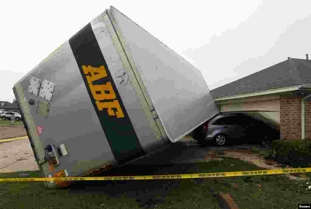 A trailer blown into a home on Lindsay Lane in Cleburne rests on a car after a tornado touch down in Cleburne, Texas. At least six people were killed and seven were missing after as many as 10 tornadoes ripped through north-central Texas.