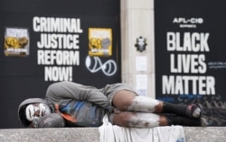 A man sleeps on a bench in front of Black Lives Matter protest signs near the White House in Washington, U.S., June 10, 2020. REUTERS/Kevin Lamarque
