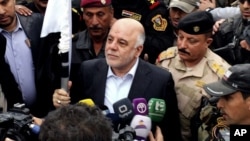 Iraqi Prime Minister Haider al-Abadi, center, raises an Iraqi flag in the city of Ramadi, 70 miles (115 kilometers) west of Baghdad, after it was retaken by the security forces, Dec. 29, 2015. 