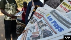 Quelques passants devant des journaux vendus dans la rue à Ouagadougou, Burkina Faso, en janvier 2016.