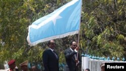 Somalia's newly elected President Mohamed Abdullahi Mohamed, right, flanked by outgoing president Hassan Sheikh Mohamud carries their national flag during the hand-over ceremony at the Presidential palace in Somalia's capital Mogadishu, Feb. 16, 2017. 