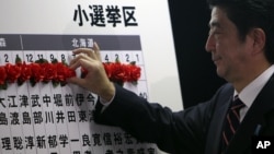 Japan's main opposition leader Shinzo Abe of the Liberal Democratic Party (LDP) marks on the name of one of those elected in parliamentary elections at the party headquarters in Tokyo, December 16, 2012. 