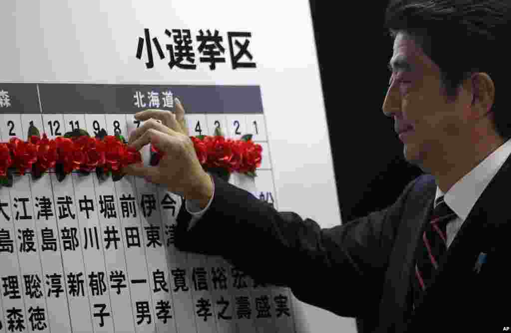 Japan's main opposition leader Shinzo Abe of the Liberal Democratic Party (LDP) marks on the name of one of those elected in parliamentary elections at the party headquarters in Tokyo, December 16, 2012. 