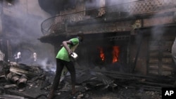 Un homme essayant de contenir l'incendie d'une maison et un entrepot a Lagos Island, Lagos, Nigeria, December 26, 2012.