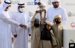 Victorious camel breeders accept a trophy for their camel at Al Dhafra Festival in Liwa desert area 120 kilometres (75 miles) southwest of Abu Dhabi, United Arab Emirates, Dec. 22, 2021.