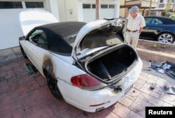 A man looks at a BMW car that was damaged by a lightning strike on Haynes Lane in a residential area of Redondo Beach, California, July 27, 2014.