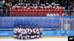 Pendukun tim Korea Utara, atas, melambaikan bendera unifikasi pada saat pemain tim hoki gabungan Kedua Korea berkumpul di akhir laga hoki perempuan melawan Swiss, di Olimpiade Musim Dingin 2018 di Gangneung, Korea Selatan, 10 Februari, 2018.