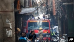 Sebuah mobil pemadam kebakaran yang berupaya melewati gang yang terlalu sempit untuk dilalui kendaraan, tersangkut kabel listrik di dekat lokasi kebakaran di New Delhi, India, Minggu, 8 Desember 2019.