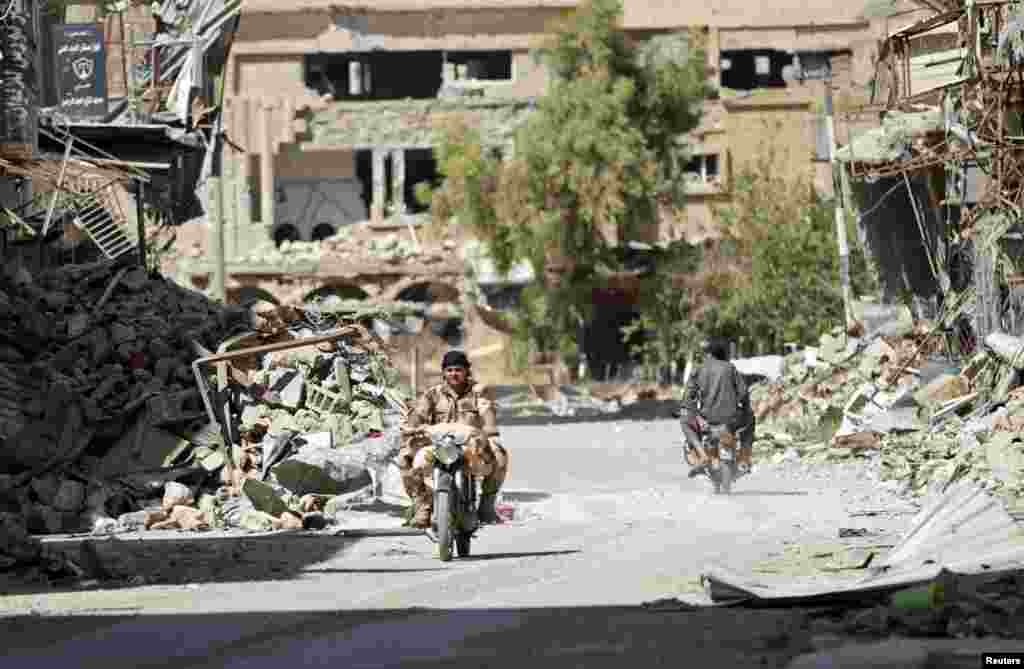 A Free Syrian Army fighter rides a motorcycle along a damaged street, Deir al-Zor, August 19, 2013. 