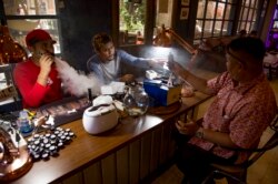 Seorang karyawan kafe rokok elektrik (kiri) melayani pembeli di Jakarta, 9 Januari 2018. (Foto: AFP)