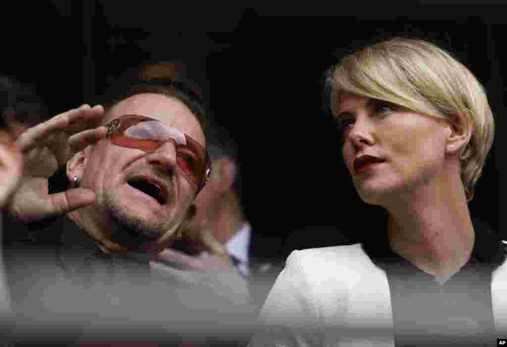 Actress Charlize Theron speaks with musician Bono before the memorial service for Nelson Mandela at the FNB Stadium in Soweto near Johannesburg, Dec. 10, 2013.
