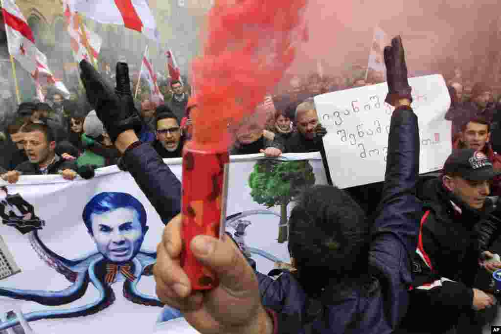 Protesters carry Georgian flags and a poster showing a caricature of former Prime Minister billionaire Bidzina Ivanishvili during a march in support of Rustavi 2 TV channel in Tbilisi. Hundreds of people marched to express their support for the independent channel and blamed the government and Ivanishvili for an attempt to silence opposition media.