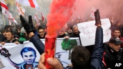 FILE - Protesters carry Georgian flags and a poster showing a caricature of former Prime Minister billionaire Bidzina Ivanishvili during a march in support of Rustavi 2 TV channel in Tbilisi, Georgia, Feb. 10, 2017.
