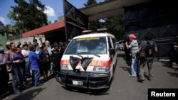 FILE - An ambulance carrying the bodies of those killed in the fire exits the Virgen de Asuncion home, in San Jose Pinula, on the outskirts of Guatemala City, Guatemala, March 8, 2017. 